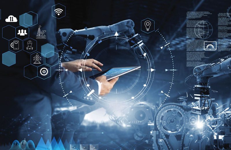 Engineer uses tablet to control robotic arms surrounded by digital data overlays and hexagon icons in smart factory.