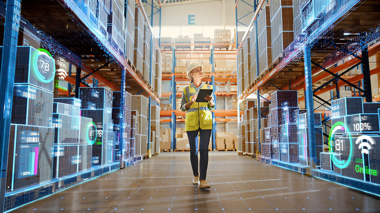 Worker in safety vest walks through smart warehouse aisle with tablet, surrounded by digital inventory data overlays.