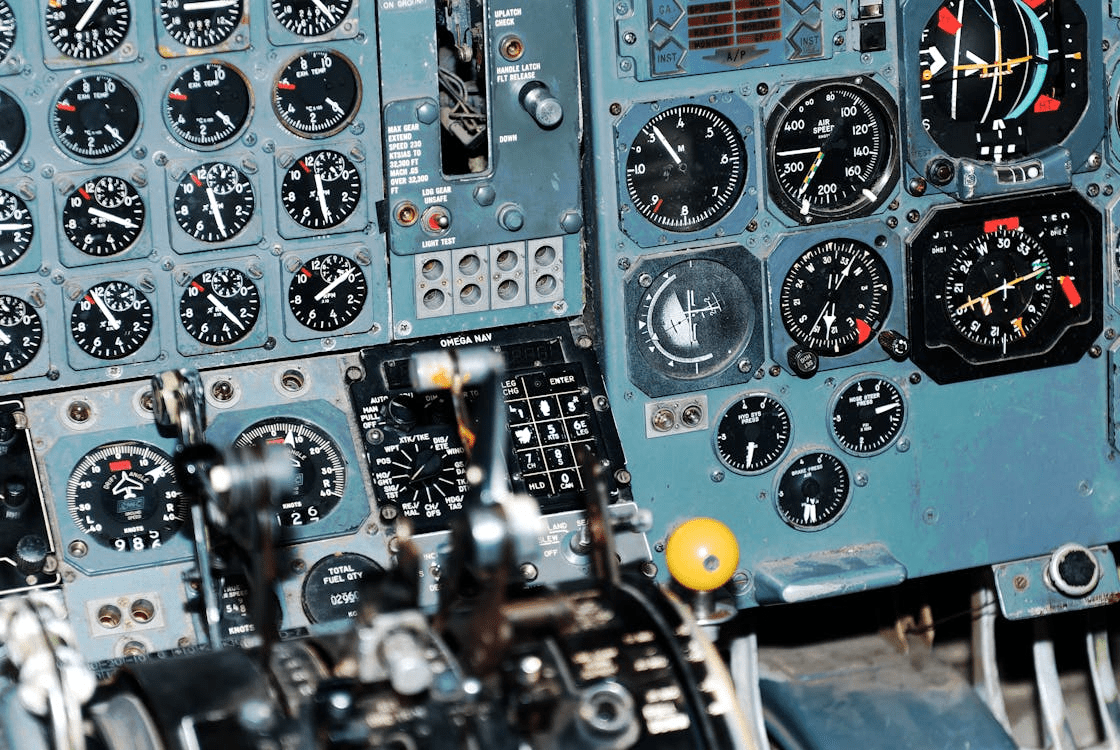 Close-up of aircraft cockpit instrument panel filled with analog gauges, dials and controls in an older airplane.